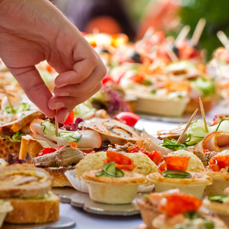 Buffet mit Appetizern und einer Hand die nach einem Häppchen greift